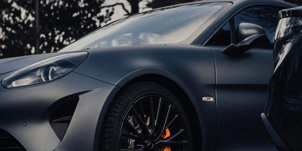 Close-up of a polished gray sports car showing a glossy finish and front wheel.