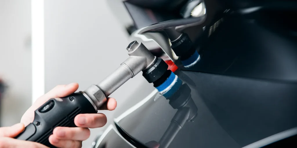 Detailer using a mini polisher with a small foam pad in a tight area of a vehicle